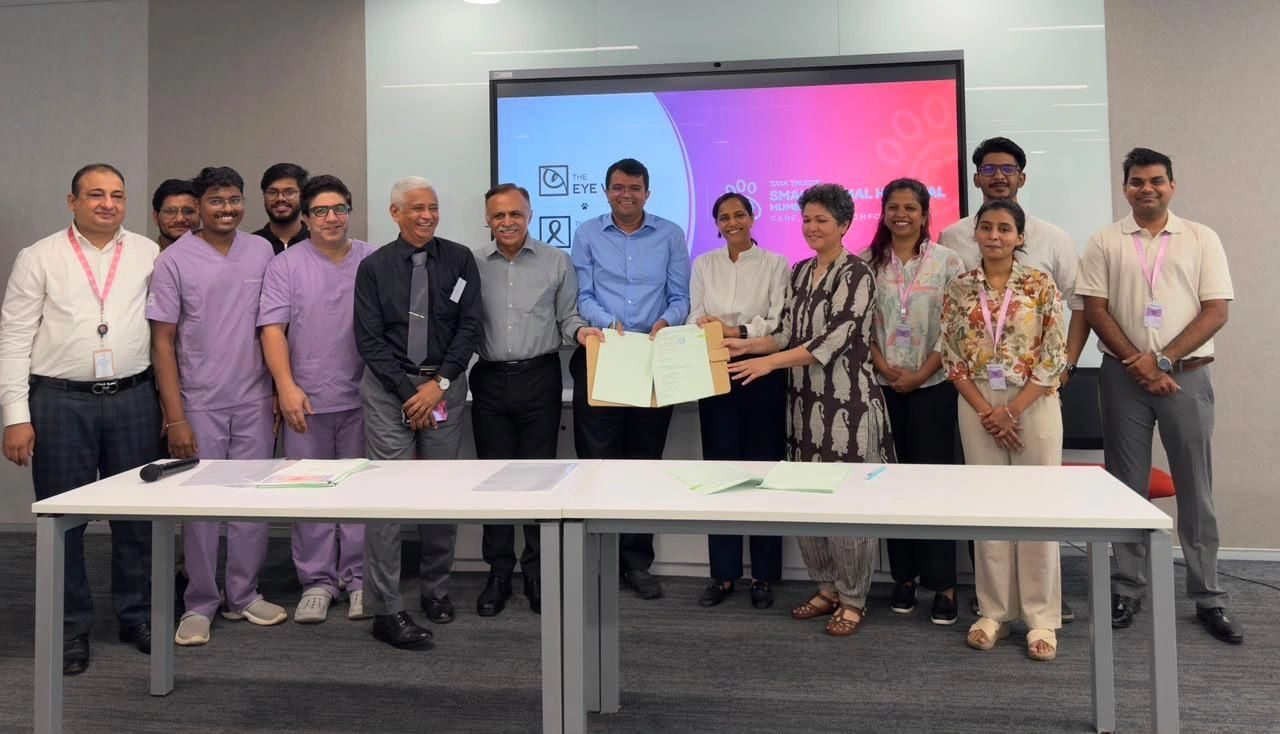 Clinicians and hospital staff gathered for the signing, two people holding open the signed agreement between them, with The Eye Vet and Small Animal Hospital Mumbai branding on the screen behind