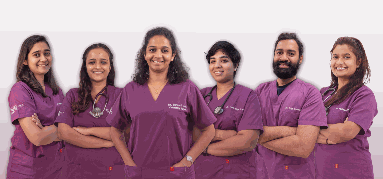 A studio group portrait of the clinical team in branded aubergine scrubs